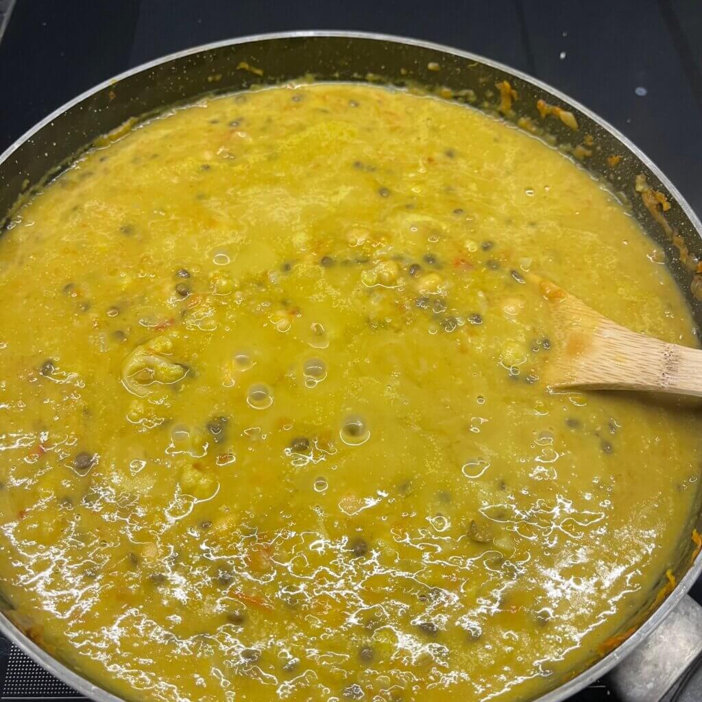 Vegetable curry with lentils, chickpeas and pumpkin simmering in a pan